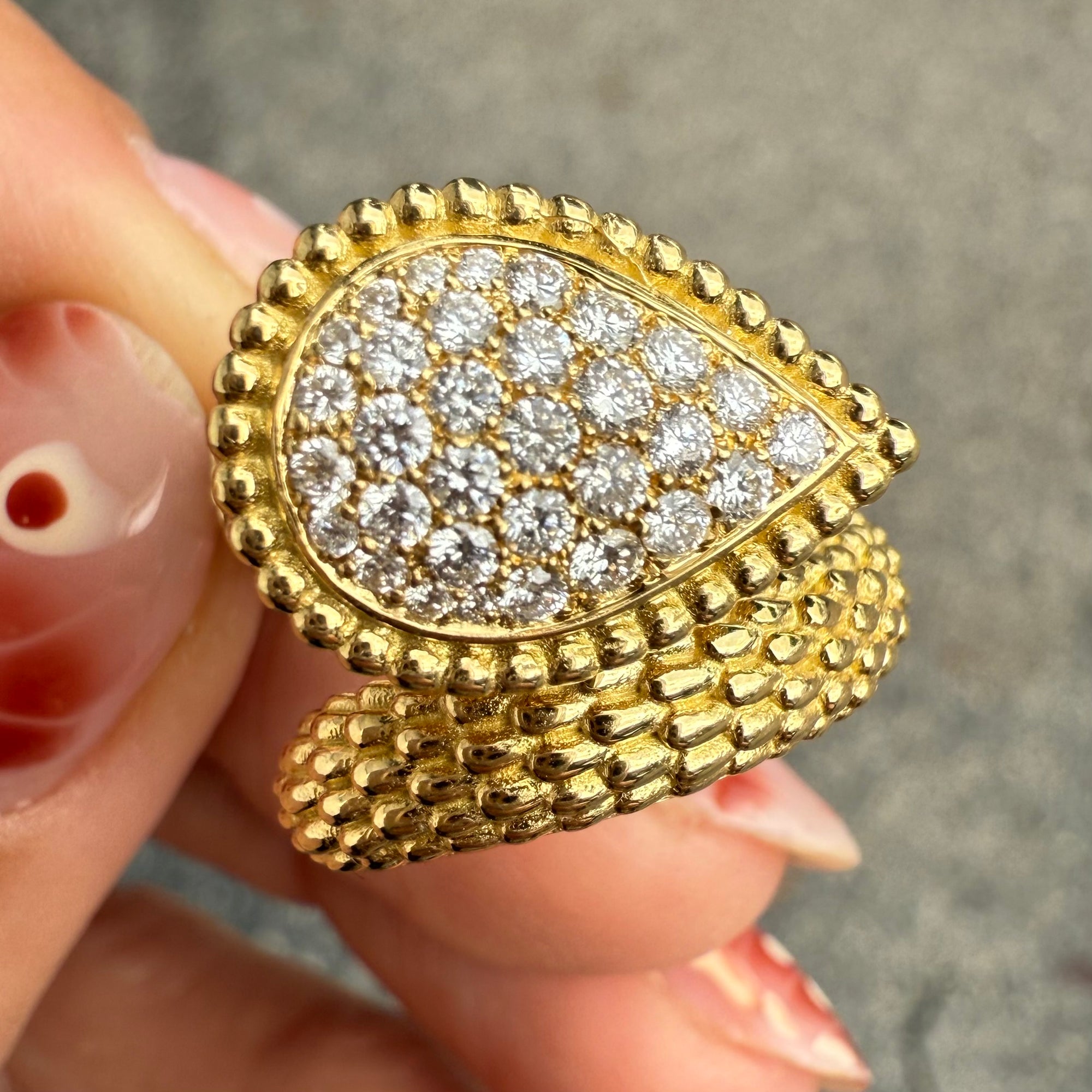 Close-up of pear-shaped diamond cluster ring with snakeskin-inspired gold texture