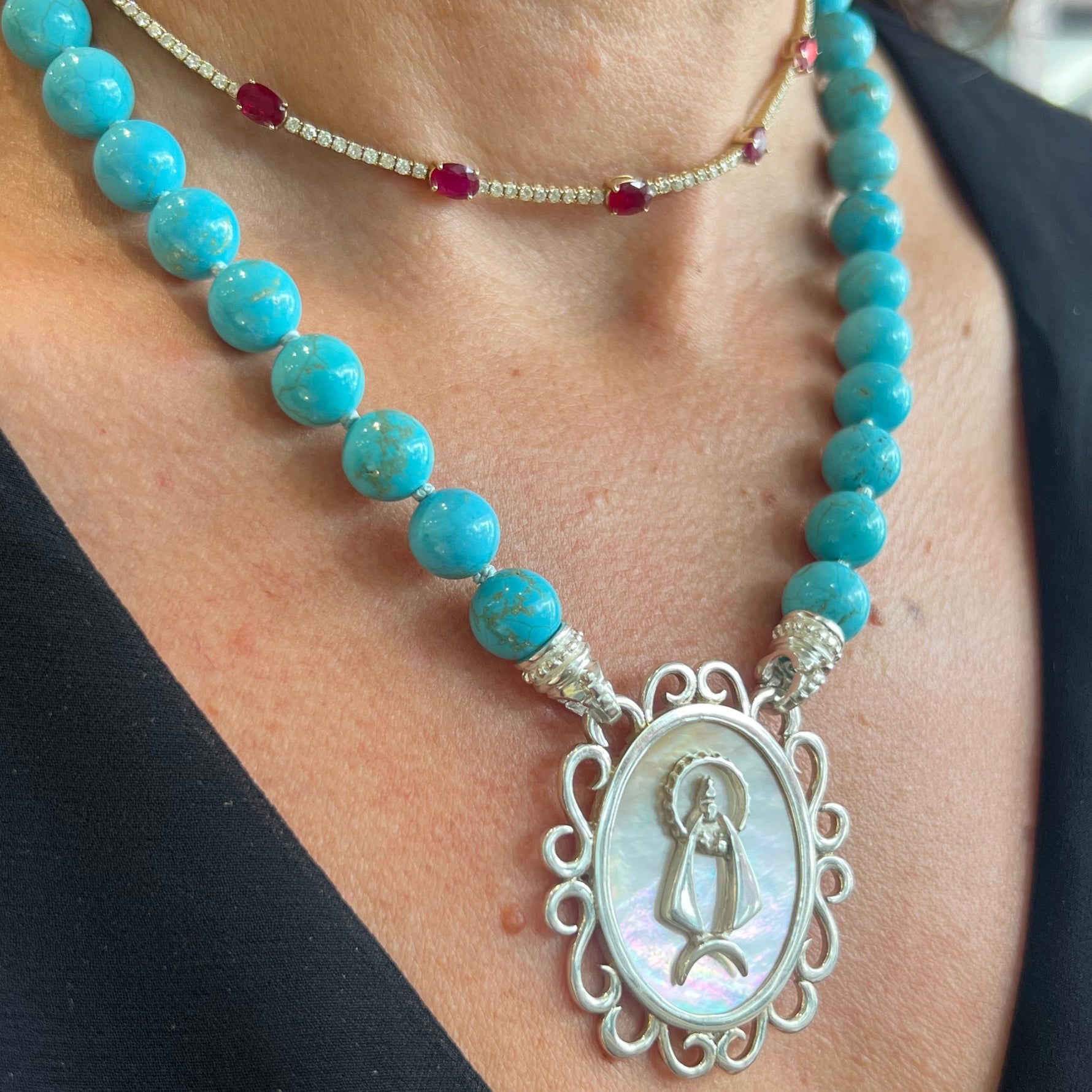 Mother of pearl pendant featuring La Caridad del Cobre on a turquoise interchangeable necklace. 