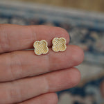 Clover shaped earrings with diamonds between fingers.
