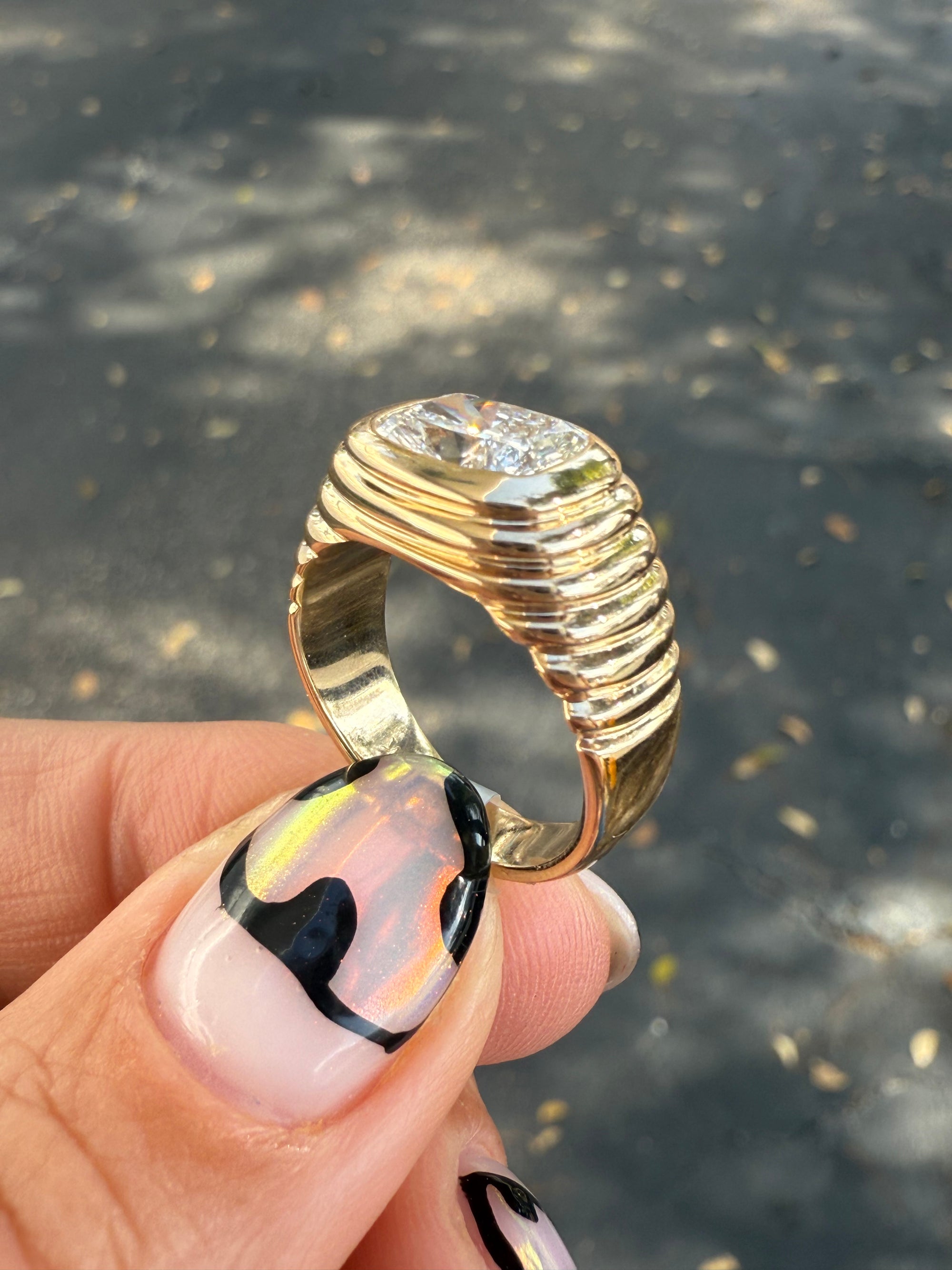 Side view of a pinky ring featuring a 2 carat cusion cut diamond. 