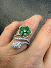 Emerald clover flower and diamond statement ring in 18K gold, worn on a hand 