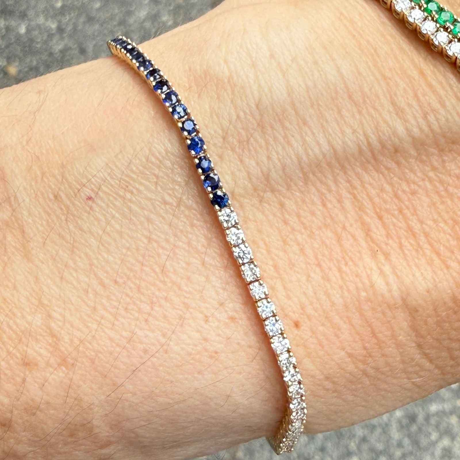 Sapphire and diamond half tennis bracelet in 14K gold on a wrist.