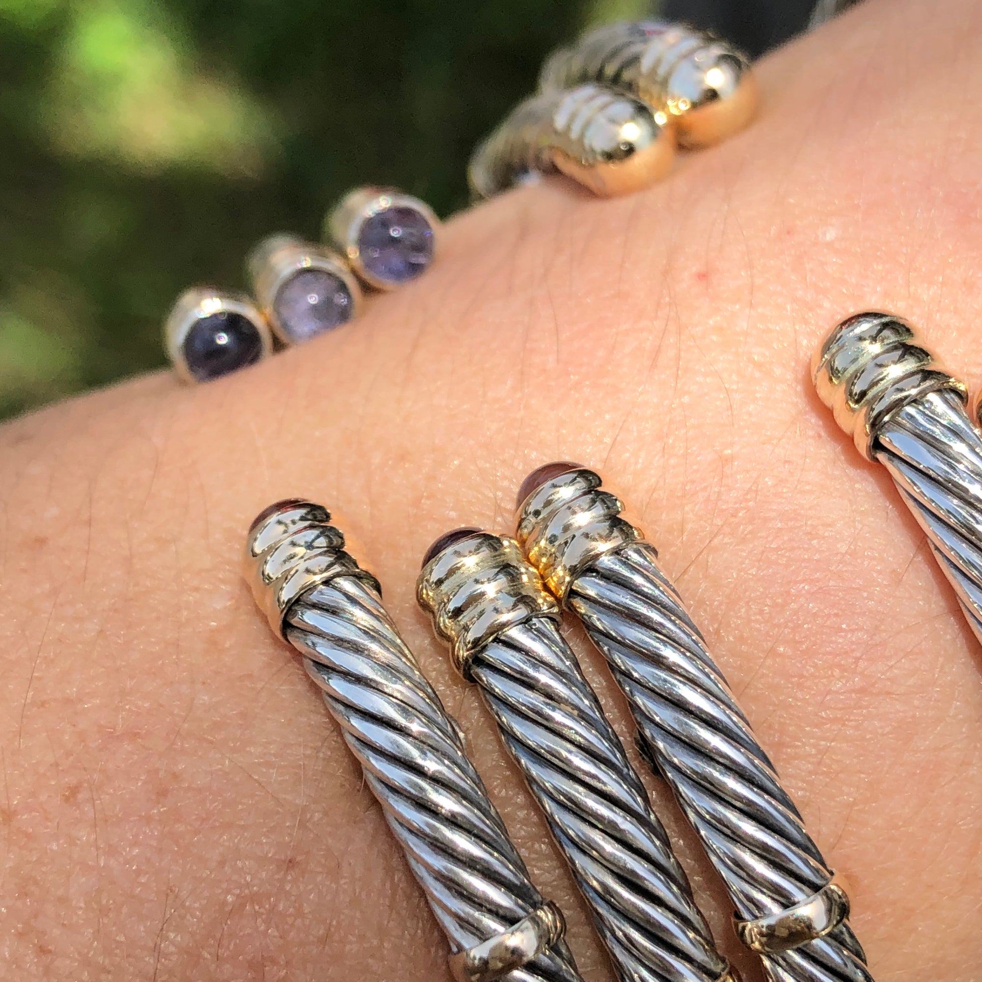 Closeup of 14k and sterling silver twist bangles on a person&#39;s arm
